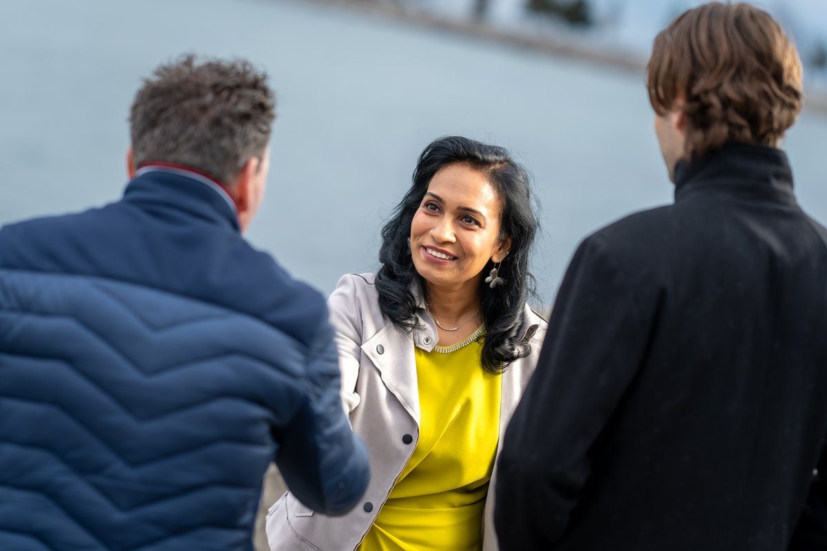 Sharmina Nasrin greeting community members outdoors near the water