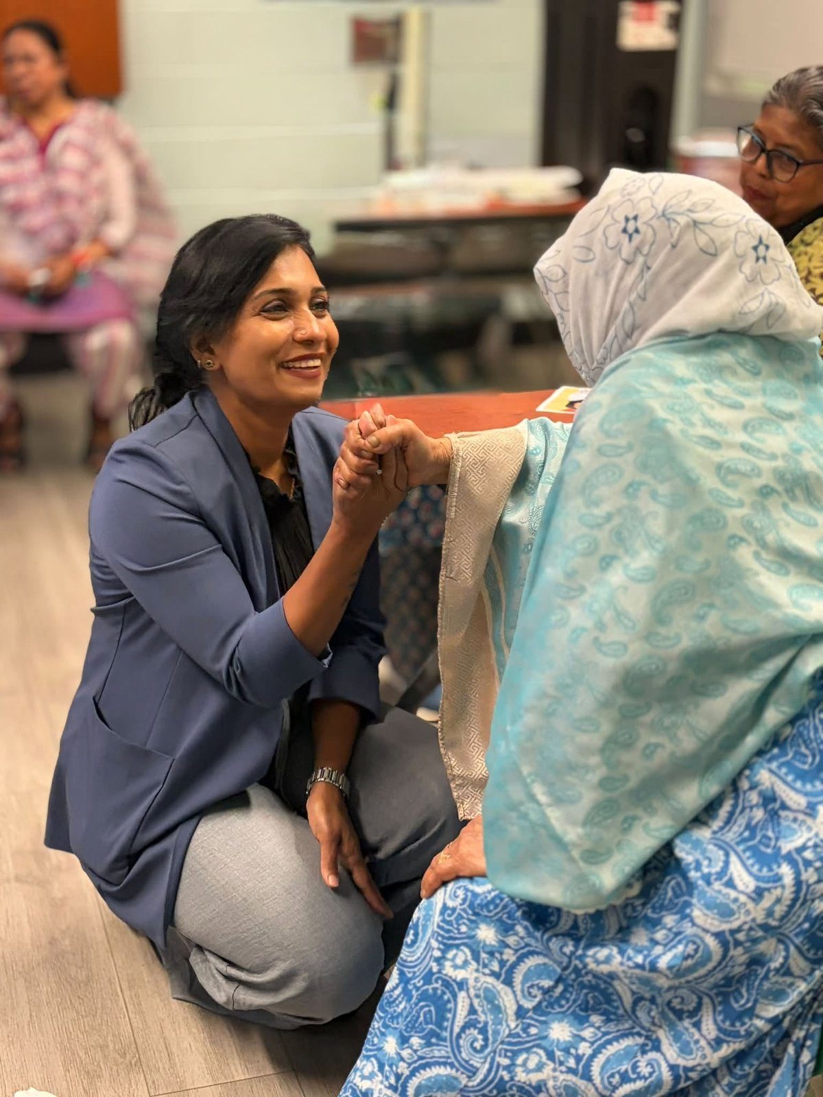 Sharmina Nasrin kneeling and holding hands with a senior resident